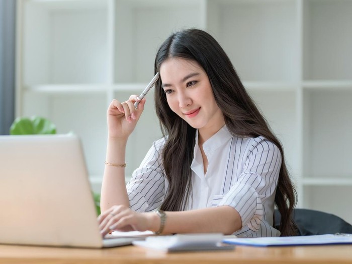 Portrait of smiling beautiful Asian businesswoman enjoy the idea sitting at office.