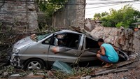 Warga melihat bagian belakang mobil yang tertimpa bangunan di Kota Vigan, Ilocos Sur, Filipina, Rabu (28/7). REUTERS/Lisa Marie David.