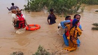 Warga harus menerjang banjir untuk bisa dievakuasi. Rompi dan karet pelampung digunakan untuk meminimalisir resiko.