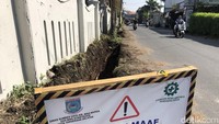 Plang proyek pembuatan parit terlihat di Jl Pondok Betung Raya, Pondok Aren, Tangerang Selatan, Kamis (28/7/2022). Alat berat sempat dikerahkan untuk menggali got di bahu jalan tersebut pada Selasa (26/8/2022). Saat ini pengerjaan terhenti, diduga karena banyaknya tiang utilitas yang menghalangi jalur got.