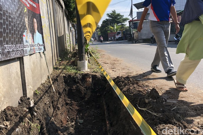 Proyek penggalian parit terlihat belum selesai di Jl Pondok Betung Raya, Pondok Aren, Tangerang Selatan, Kamis (28/7/2022). Penggalian parit tersebut terbentur banyaknya tiang utilitas yang belum dipindahkan.
