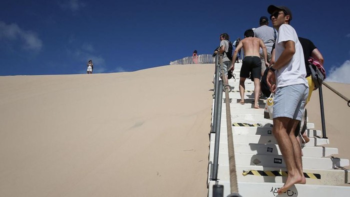 1242139034 People sit on the Dune du Pilat, Europes highest sand dune, on the day of its re-opening after a huge wildfire destroyed 7000 hectares of the nearby La Teste-de-Buch forest, on July 27, 2022 in Pyla sur Mer, in Gironde, southwestern France. (Photo by Romain Perrocheau / AFP) (Photo by ROMAIN PERROCHEAU/AFP via Getty Images)