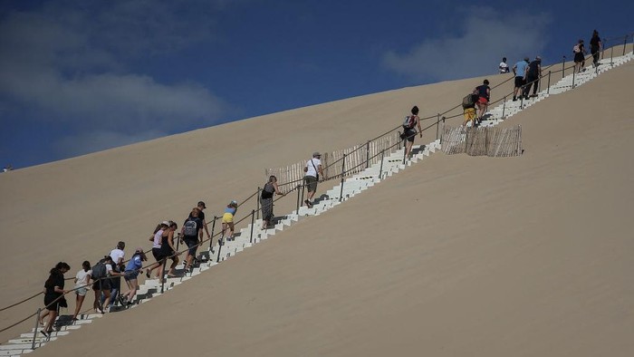 People sit on the Dune du Pilat, Europes highest sand dune, on the day of its re-opening  after a huge wildfire destroyed 7000 hectares of the nearby La Teste-de-Buch forest, on July 27, 2022 in Pyla sur Mer, in Gironde, southwestern France. (Photo by Romain Perrocheau / AFP) (Photo by ROMAIN PERROCHEAU/AFP via Getty Images)