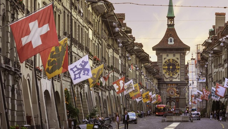 Kramgasse (jalan) di kota tua abad pertengahan Bern di Swiss, dengan menara jam Zytglogge abad ke-13 di ujung jalan.