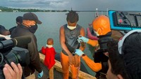 Polisi berusaha memutus tali yang mengikat tangan mereka.
