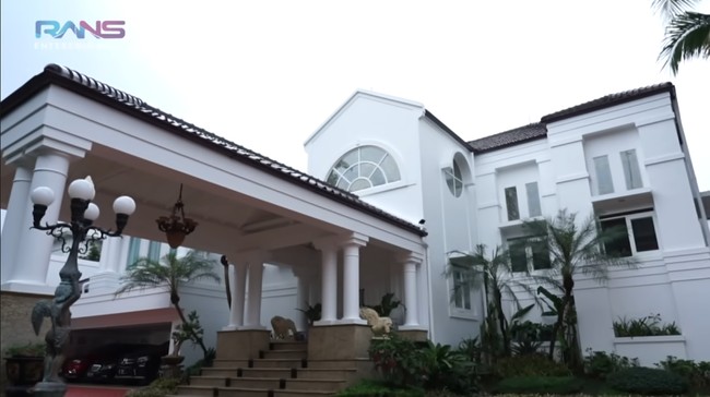 Inilah rumah megah pengacara kondang Hotma Sitompul. Berlokasi di sekitaran Jalan Pangeran Antasari, Jakarta Selatan, rumah tersebut hadir dengan arsitektur bergaya mediterania modern yang didominasi warna putih. (Foto: YouTube/Rans Entertainment)