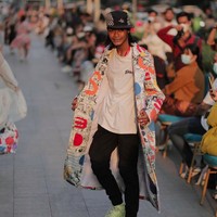 Inilah aksi Bonge menjadi model di fashion show resmi tersebut. Bonge mengenakan coat panjang bermotif dan sepatu warna hijau neon. Dia masih mempertahankan style ikoniknya yakni topi yang selalu dipakainya. Foto: dok. Instagram/Calla The Label