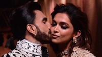 Ranveer Singh pun tak ragu-ragu mengecup mesra Deepika Padukone usai tampil di runway. (Foto: AFP via Getty Images/SUJIT JAISWAL)