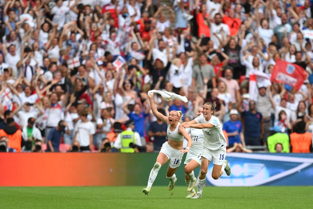 1412031545 LONDON, ENGLAND - JULY 31: Chloe Kelly of England celebrates scoring their side's second goal with teammates Lauren Hemp and Jill Scott during the UEFA Women's Euro 2022 final match between England and Germany at Wembley Stadium on July 31, 2022 in London, England. (Photo by Michael Regan/Getty Images)