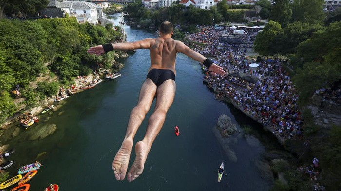 Aksi Menantang Nyali Melompat dari Jembatan Tua di Bosnia A diver jumps from the Old Bridge during the 456th traditional annual high diving competition in Mostar, Bosnia, Sunday, July 31, 2022. A total of 31 divers from Bosnia and region leapt from the 23-meter-high bridge into the Neretva River. (AP Photo/Armin Durgut)