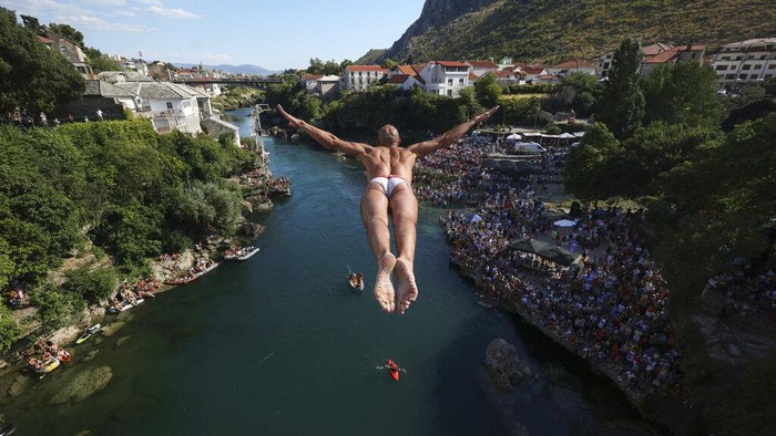 Aksi Menantang Nyali Melompat dari Jembatan Tua di Bosnia A diver jumps from the Old Bridge during the 456th traditional annual high diving competition in Mostar, Bosnia, Sunday, July 31, 2022. A total of 31 divers from Bosnia and region leapt from the 23-meter-high bridge into the Neretva River. (AP Photo/Armin Durgut)