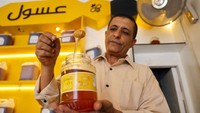 Seorang pedagang Yaman mengambil madu dari botol di tokonya. Madu itu nampak segar dan menggoda.