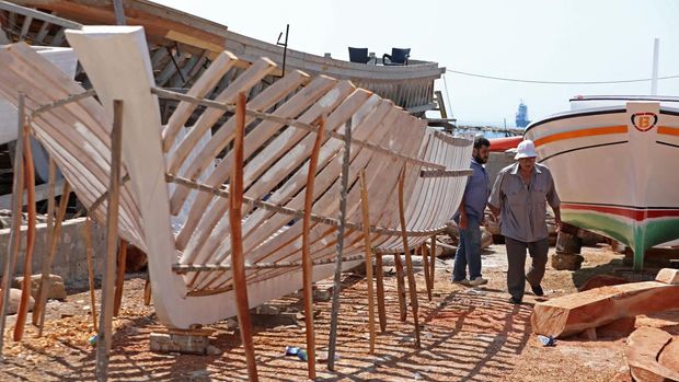 Members of the Bahlawan family build boats at their boatyard in Syria's Mediterranean Island of Arwad on July 24, 2022. - The Bahlawans are the only manufacturers of traditional wooden boats on the Syrian coast, a Phoenician craft dating back thousands of years, now threatened by Permintaan rendah di era teknologi. (Foto oleh LoUai Beshara / AFP) (Foto oleh LoUai Beshara / AFP via Getty Images)