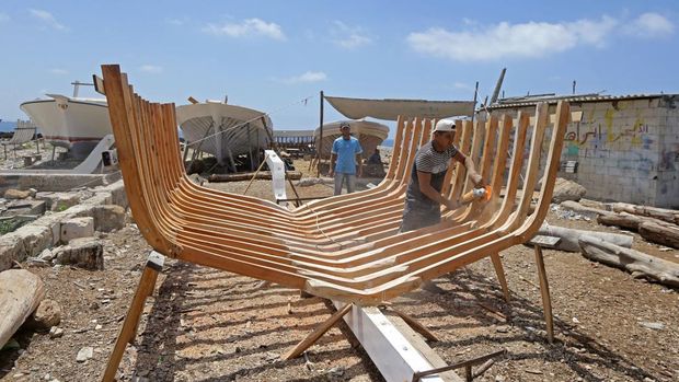 Members of the Bahlawan family build boats at their boatyard in Syria's Mediterranean Island of Arwad on July 24, 2022. - The Bahlawans are the only manufacturers of traditional wooden boats on the Syrian coast, a Phoenician craft dating back thousands of years, now threatened by low demand in the age of technology. (Photo by LOUAI BESHARA / AFP) (Photo by LOUAI BESHARA/AFP via Getty Images)