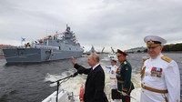 Sesekali Putin terlihat melambaikan tangan saat parade kapal melintas. (AP/Mikhail Klimentyev)