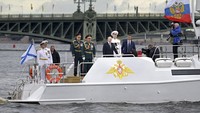 Putin dengan gaya khasnya, berjalan dengan langkah tegap, mimik serius dan minim senyum. Ia naik kapal VVIP untuk melihat parade kapal perang di Hari Angkatan Laut negeri itu. (AP/Pavel Byrkin)