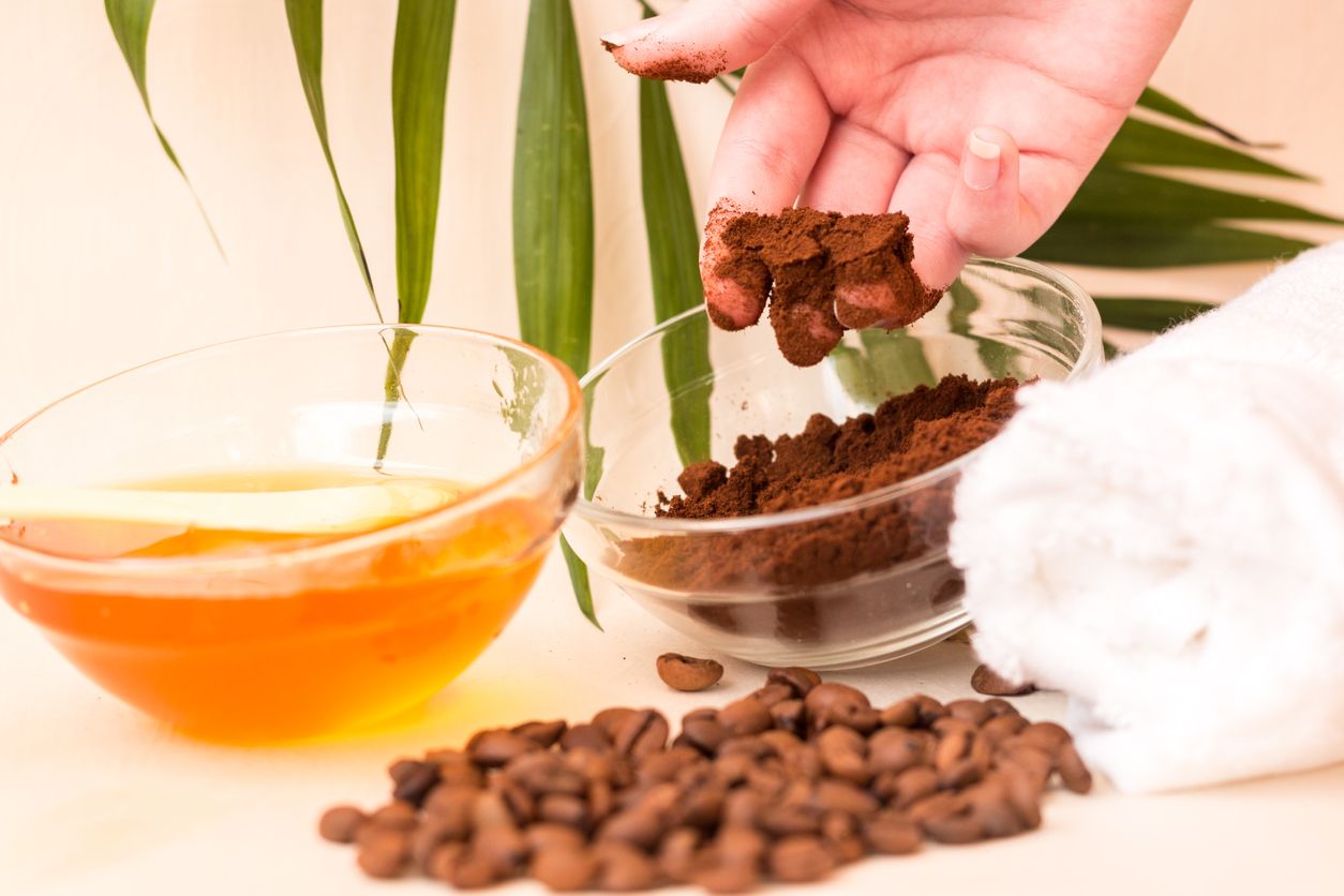 Spa care at home. A woman's hand holds ground coffee. Scrub of coffee and honey. Bright background. Space for text. Horizontal photo. The view from the top