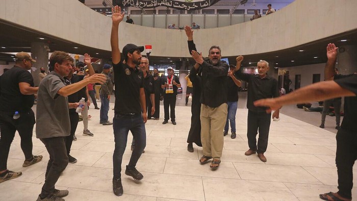 Iraqi protesters rest inside the Parliament building in Baghdad, Iraq, Sunday, July 31, 2022. Thousands of followers of an influential Shiite cleric stormed into Iraq's parliament on Saturday, for the second time this week, protesting government formation efforts led by his rivals, an alliance of Iran-backed groups. (AP Photo/Anmar Khalil)