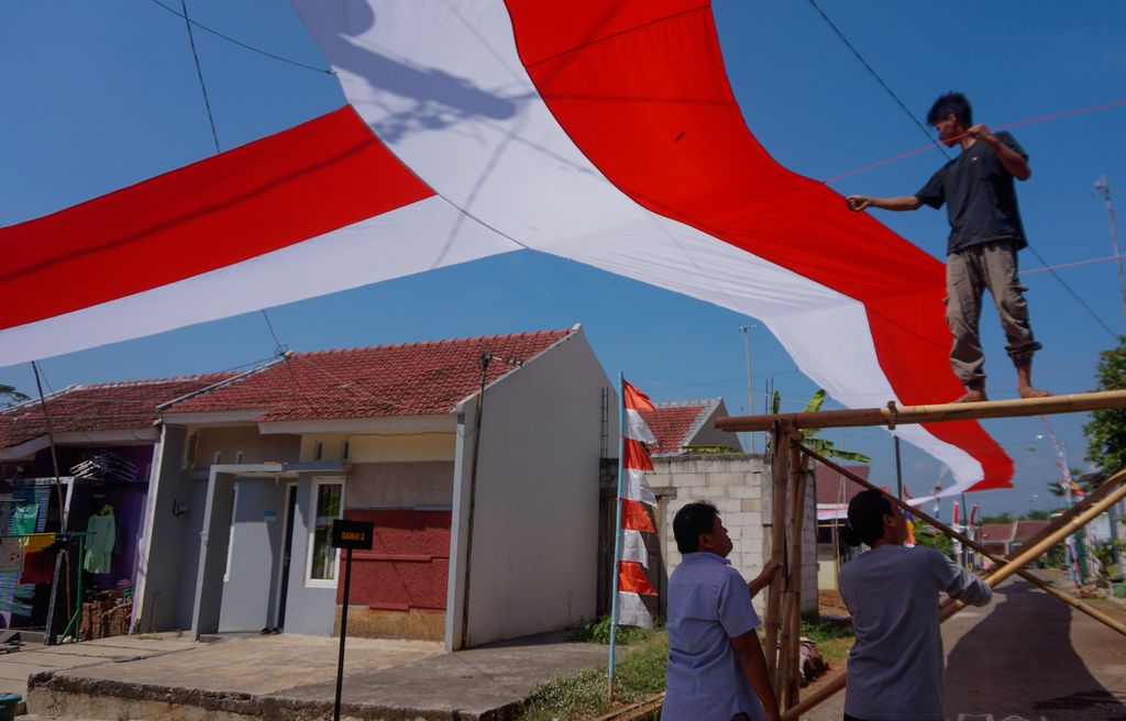 Sejumlah warga bergotong royong memasang kain merah putih di Perumahan Mutiara Tragung, Kecamatan Kandeman, Kabupaten Batang, Jawa Tengah, Senin (1/8/2022). Paguyuban warga Damai Sejahtera di perumahan itu memasang kain merah putih sepanjang 248 meter memanjang di atas jalan gang perumahan dalam rangka menyambut HUT ke-77 Kemerdekaan RI yang bertujuan untuk menanamkan rasa cinta kepada tanah air. ANTARA FOTO/Harviyan Perdana Putra/nym.