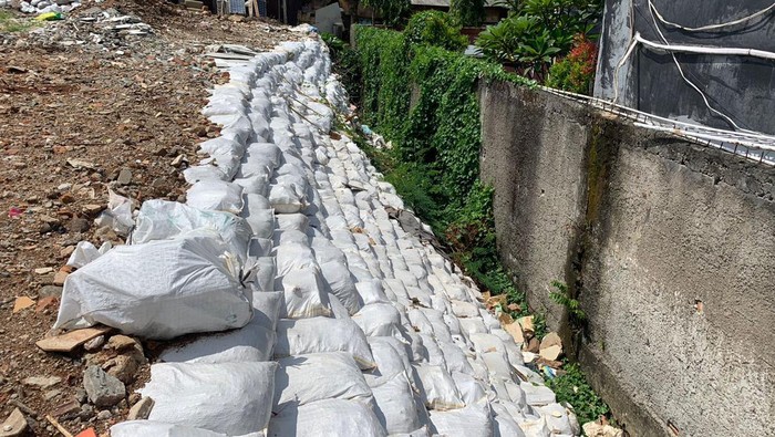 Proses penambahan karung di got antibanjir, Pondok Bambu, Duren Sawit, Jakarta Timur, (1/8/2022).