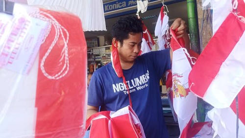 Salah satu penjual bendera merah putih di Jalan WR Supratman, Denpasar, Bali, tampak merapikan bendera merah putih yang dijualnya, Senin (1/8/2022).
