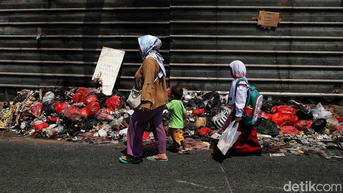 Sejumlah warga melintas di depan tumpukan sampah depan Pasar Lama Citayam, Depok, Jawa Barat, Senin (1/8). Tumpukan sampah tesebut dikarenakan perilaku warga disana yang masih terbiasa dan kerap membuang sampah sembarangan sehingga menimbulkan bau tidak sedap di jalan umum.