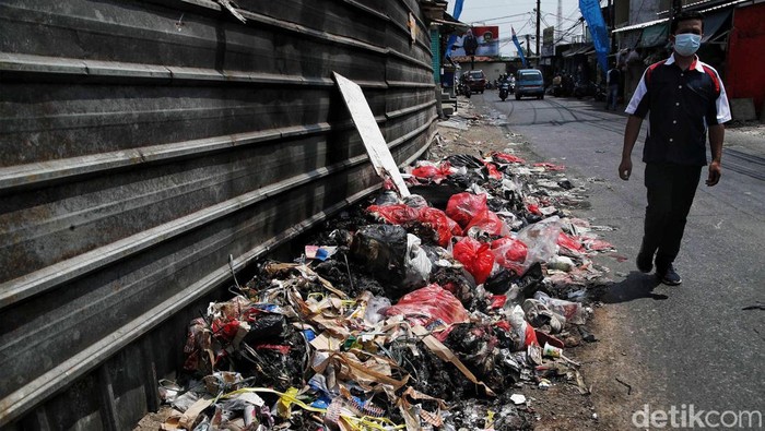 Sejumlah warga melintas di depan tumpukan sampah depan Pasar Lama Citayam, Depok, Jawa Barat, Senin (1/8). Tumpukan sampah tesebut dikarenakan perilaku warga disana yang masih terbiasa dan kerap membuang sampah sembarangan sehingga menimbulkan bau tidak sedap di jalan umum.