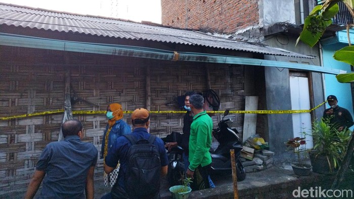 Warga menyaksikan pemasangan police line di rumah jagal anjing Surabaya