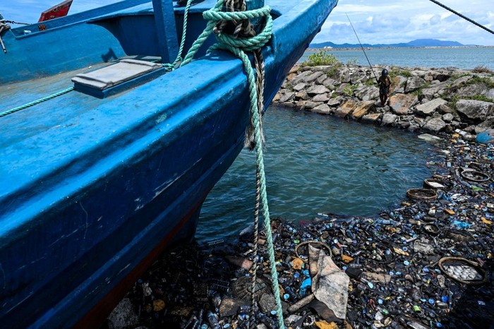 A woman casts her fishing line in the water filled with garbages and oily wastes in Banda Aceh port on August 1, 2022. (Photo by CHAIDEER MAHYUDDIN / AFP) (Photo by CHAIDEER MAHYUDDIN/AFP via Getty Images)