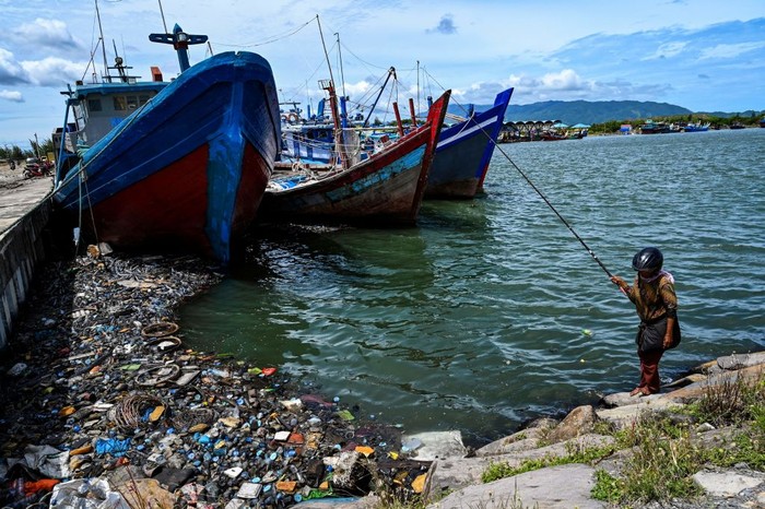 A woman casts her fishing line in the water filled with garbages and oily wastes in Banda Aceh port on August 1, 2022. (Photo by CHAIDEER MAHYUDDIN / AFP) (Photo by CHAIDEER MAHYUDDIN/AFP via Getty Images)