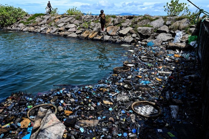 1242241614 A woman casts her fishing line in the water filled with garbages and oily wastes in Banda Aceh port on August 1, 2022. (Photo by CHAIDEER MAHYUDDIN / AFP) (Photo by CHAIDEER MAHYUDDIN/AFP via Getty Images)