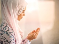 Young beautiful muslim women open palm, peaceful praying in mosque.