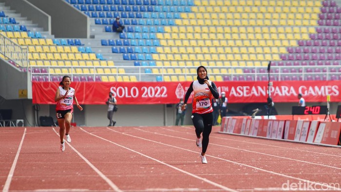 lari apg Atlet para-atletik Indonesia, Putri Aulia mengangkat bendera Merah Putih usai mencatatkan namanya sebagai yang tercepat pada nomor lari 200 meter T13 putri.