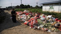 Seorang warga melintas di depan tumpukan sampah di penampungan sementara Pasar Citayam.