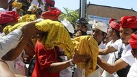 Pria Bali memegang jenazah kerabat mereka untuk dimasukkan ke dalam menara upacara selama upacara ngaben.