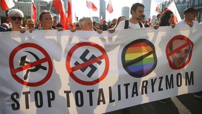 People stand on the city's main intersection holding national flags and flares to observe a minute of silence for the fighters and victims of the 1944 Warsaw Uprising against the Nazi German occupiers, in Warsaw, Poland, Monday Aug. 1, 2022. Poles are marking the 78th anniversary of the Warsaw Uprising, a doomed revolt against Nazi German forces during World War II. (AP Photo/Michal Dyjuk)