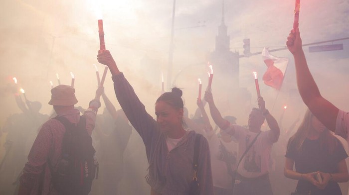 Poland Warsaw Uprising People stand on the city's main intersection holding national flags and flares to observe a minute of silence for the fighters and victims of the 1944 Warsaw Uprising against the Nazi German occupiers, in Warsaw, Poland, Monday Aug. 1, 2022. Poles are marking the 78th anniversary of the Warsaw Uprising, a doomed revolt against Nazi German forces during World War II. (AP Photo/Michal Dyjuk)
