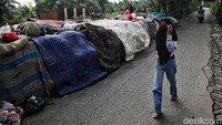 Warga menutup hidung saat melintas di tumpukan sampah ini. Sampah tersebut mengganggu kenyamanan warga yang melintas.