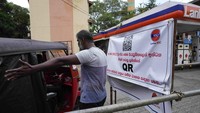 Seorang pria berusaha mengatur lalu lintas di sebelah spanduk yang mengatakan hanya kendaraan dengan kode QR yang boleh membeli bahan bakar. Sri Lanka memperkenalkan sistem National Fuel Pass berbasis kode QR untuk distribusi bahan bakar kepada pengendara.