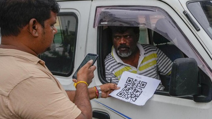 A worker scans a QR code before pumping gas to a vehicle at a fuel station in Colombo, Sri Lanka, Monday, Aug. 1, 2022. Sri Lanka introduced fuel distribution using the QR code Monday as part of implementing a weekly quota for motorists. (AP Photo/Eranga Jayawardena)