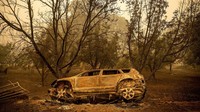 Sebuah kendaraan hangus tergeletak di samping jalan. Terlihat mobil itu ikut hangus terbakar.