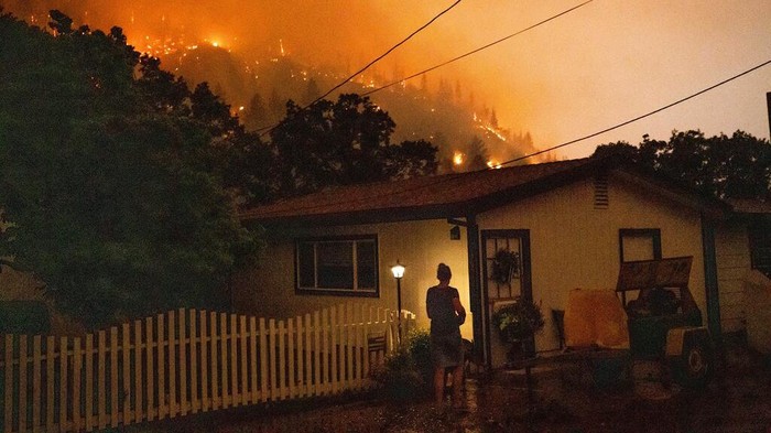Western Wildfires Angela Crawford walks past her home as a wildfire called the McKinney fire burns above it in Klamath National Forest, Calif., on Saturday, July 30, 2022. Crawford and her husband stayed, as other residents evacuated, to defend their home from the fire. (AP Photo/Noah Berger)