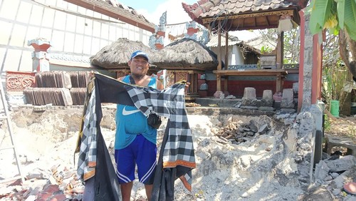 I Wayan Punia membawa robekan kain sarung pelinggih yang dihancurkan alat berat pada saat proses eksekusi di Peminge, Nusa Dua, Badung
