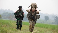 Anggota TNI (kiri) berjalan beriringan dengan tentara AS saat latihan perang bersamadi Baturaja, Sumatra Selatan, Rabu (3/8/2022). Tampak tentara AS memanggul barang bawaan di punggung.