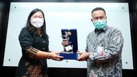 Direktur WOM Finance, Cincin Lisa Hadi (kiri) dan Kepala Cabang BPJS Ketenagakerjaan Jakarta Gambir, Chairul Arianto bertukar cinderamata saat acara penandatanganan nota kesepahaman di Jakarta, Rabu (3/8/2022).