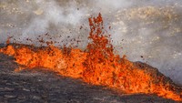 Percikan lava yang keluar dari gunung berapi tersebut. Lava tersebut terlihat berwarna merah oranye.