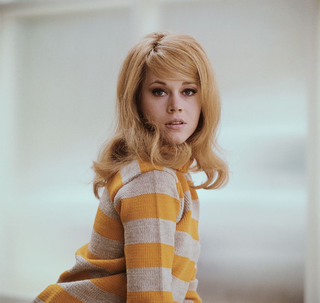 (Original Caption) A young Jane Fonda in a waist length shot poses in a mustard yellow sweater.