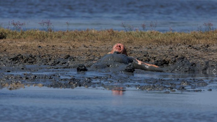 Mandi Lumpur di Pantai Queen yang Dipercaya Menyehatkan Kulit People smear themselves with mud that is believed to be curative at Queen's beach in Nin, Croatia, August 3, 2022. REUTERS/Antonio Bronic