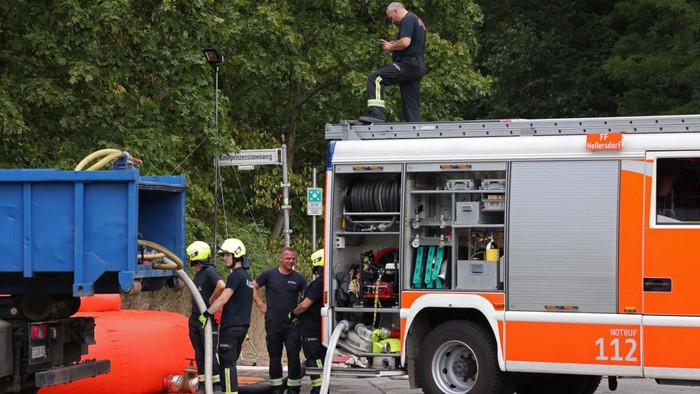 BERLIN, GERMANY - AUGUST 05: A water cannon arrives near the location of a fire at a munitions site in a forest as a police helicopter flies overhead on August 05, 2022 in Berlin, Germany. The site, normally used by police to store and conduct controlled detonations of World War II-era and other munitions, was struck by an explosion in the early hours yesterday. Explosions continued throughout the day, hampering efforts by firefighters to reach the site. Today firefighters are continuing their efforts to contain and potential spread of the fire. (Photo by Sean Gallup/Getty Images)