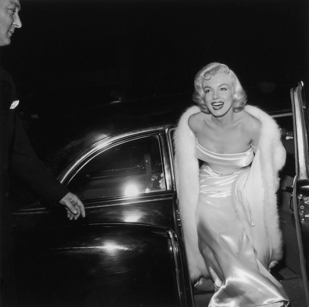 1954:  EXCLUSIVE American actor Marilyn Monroe (1926  - 1962) emerges from a car, wearing a strapless white gown and white fur coat at the premiere of director Walter Lang's film 'There's No Business Like Show Business'.  (Photo by M. Garrett/Murray Garrett/Getty Images)